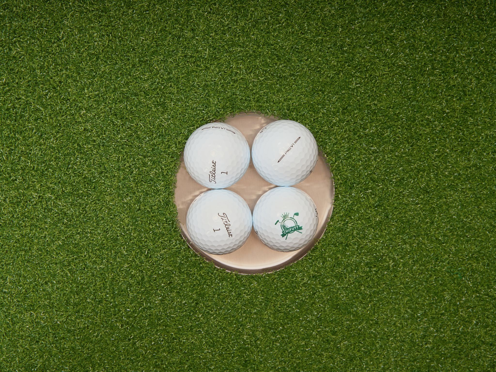 Four golf balls arranged on artificial turf, perfect for practice setups.