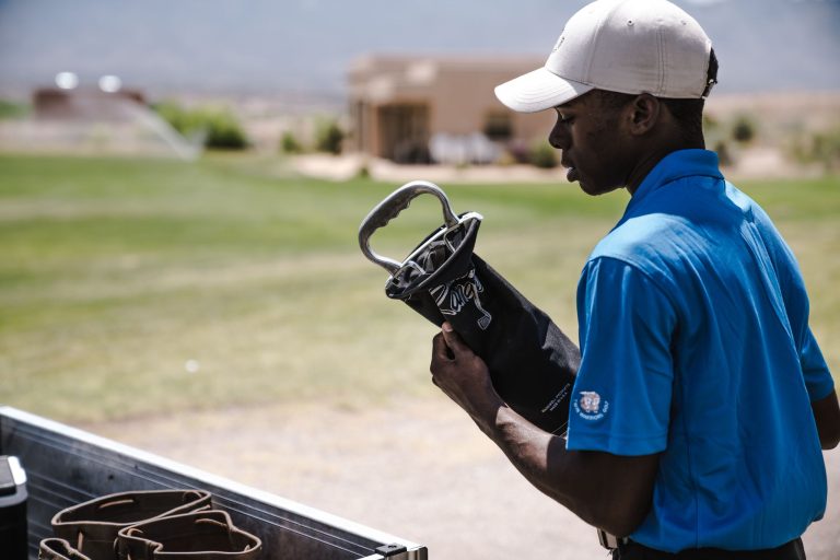 Man organizing golf clubs on a sunny day at a golf course, showcasing outdoor sports equipment.